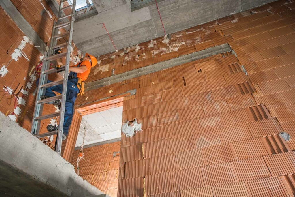 Construction Worker on a Ladder Inspecting Commercial Building