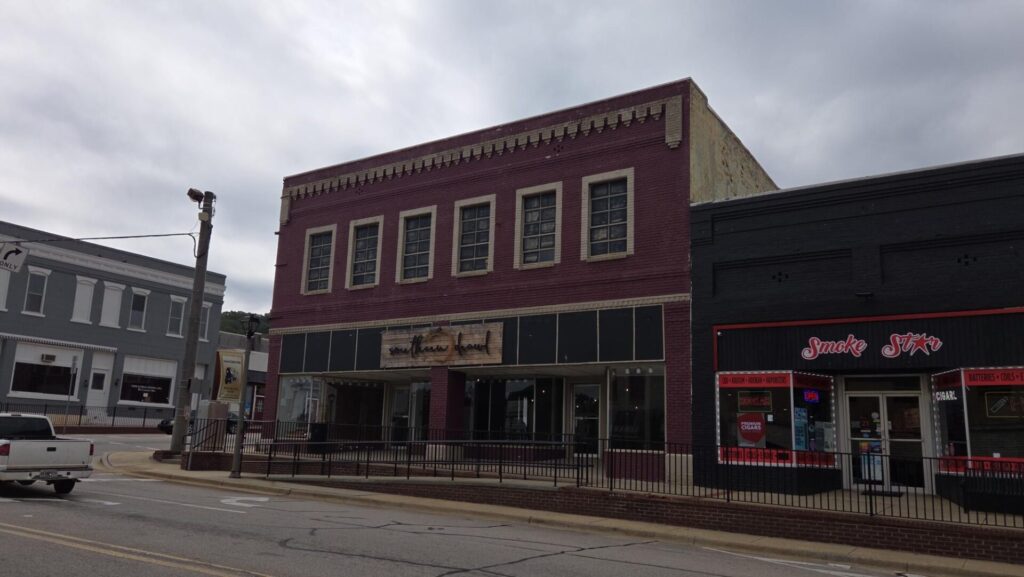 A street view of several small businesses in low-rise brick buildings on a cloudy day.